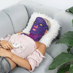 Woman-lying-down-sleeping-with-Equinox-Pro-LED-mask-on-face,-neck-and-chest-with-warm-glowing-red-light-activated